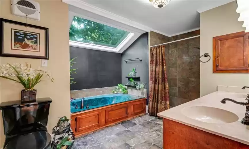 Imagine stepping into your luxurious ensuite primary bathroom. The first thing that catches your eye is the garden tub, a haven of relaxation. It's beautifully nestled against a large window, allowing natural light to stream in, creating a warm and inviting atmosphere.