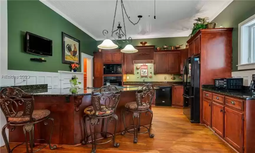 In this inviting Southern kitchen, you'll find a cozy breakfast bar that beckons you to start your day with a smile. The wood cabinetry, with its rich, timeless design, exudes that classic Southern touch. These cabinets offer ample storage space, so you can keep your kitchen well-organized.