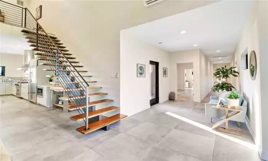 FLOATING WORK OF ART STAIRCASE WITH IRON RAILING AND LIVE EDGE SLAB TREADS. HALLWAY TO GUEST ROOMS (EACH WITH ACCESS TO THE POOL).