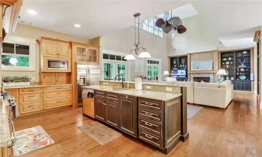 Warm wood tones on flooring and cabinetry in kitchen.