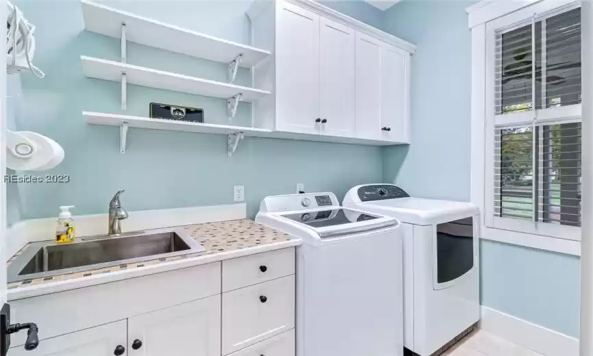 Spacious laundry room with work sink and window.