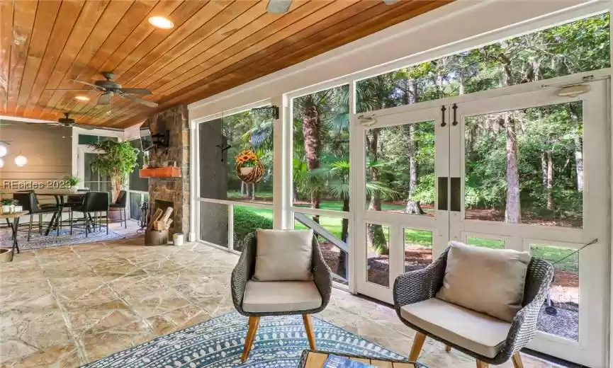 Screened back porch with wood fireplace, stone flooring.