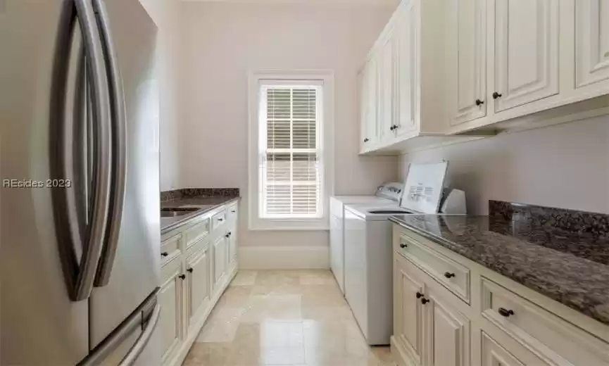 Laundry room with generous storage and refrigerator.