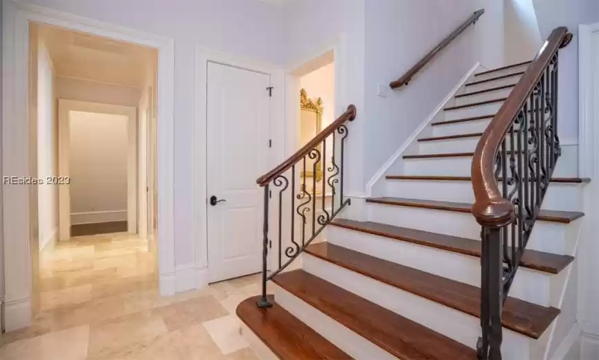 Custom ironwork staircase leading up to home theatre room with full bath and large guest room with full bath and storage.