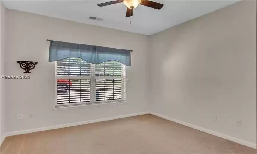 Guest bedroom number three with neutral carpet and ceiling fan/light.