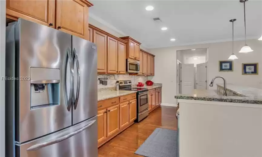 This space-saving kitchen features stainless steel appliances and the cabinetry and hard wood floors go together most attractively.