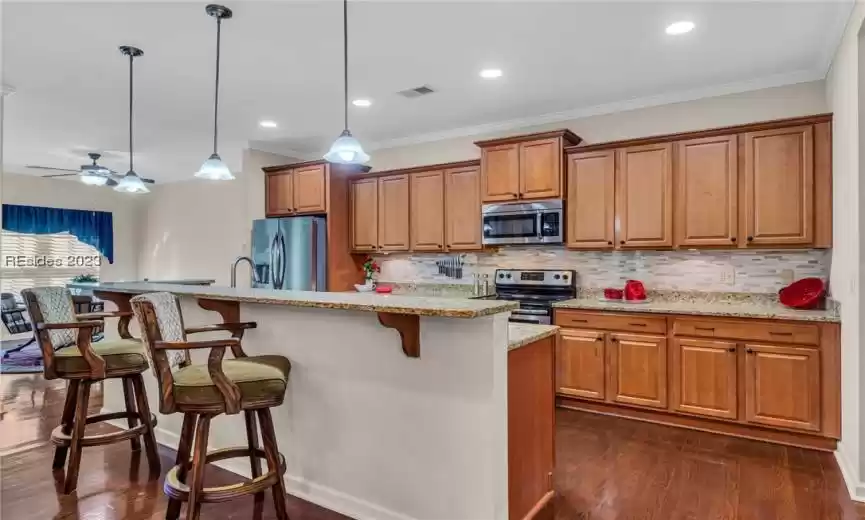 Open concept light and bright Kitchen with beautiful granite counters, backsplash, and rich wood cabinetry.