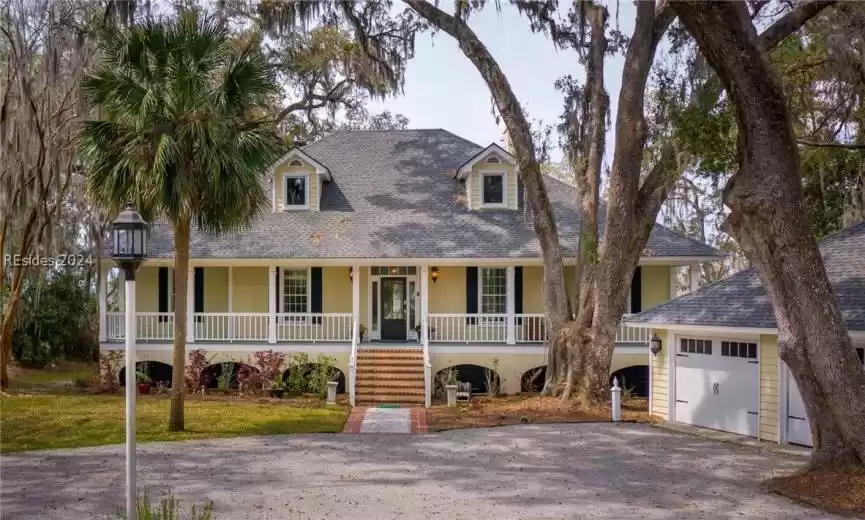View of front of home with a garage, a front yard, and a porch