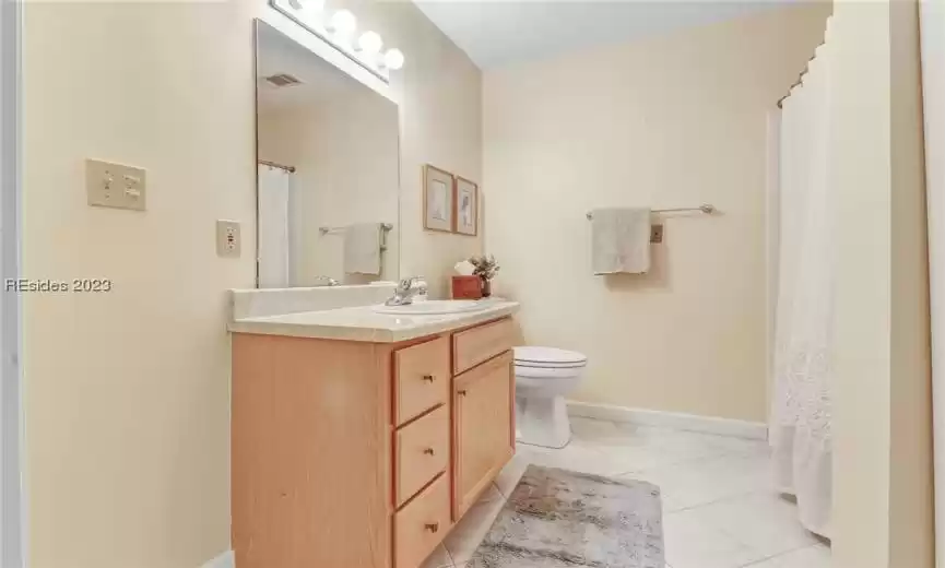 Bathroom with toilet, tile floors, and large vanity