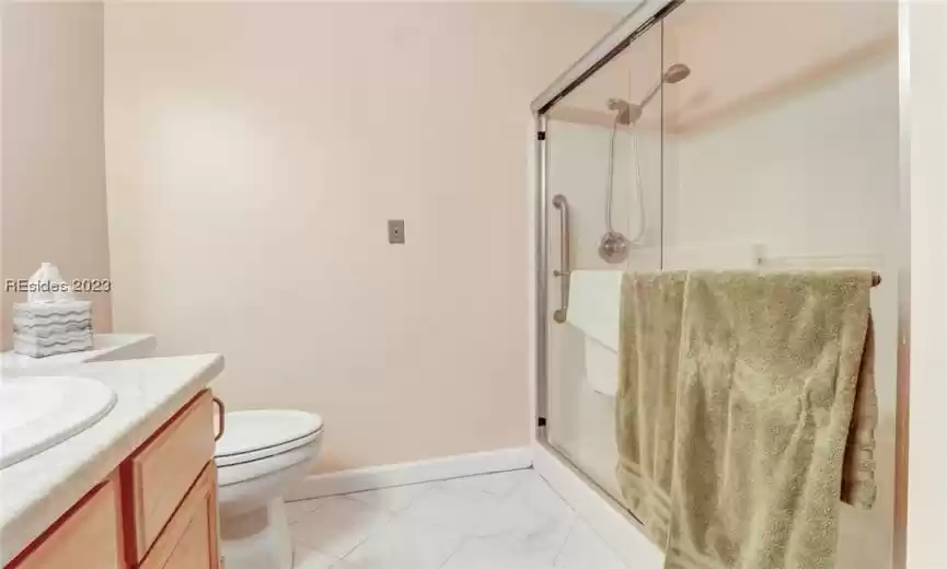 Bathroom featuring toilet, an enclosed shower, vanity, and tile flooring