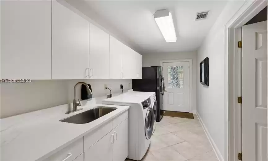 Laundry area featuring cabinets, sink, light tile floors, independent washer and dryer, and electric dryer hookup