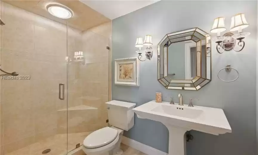 Bathroom featuring toilet, a shower with door, and sink