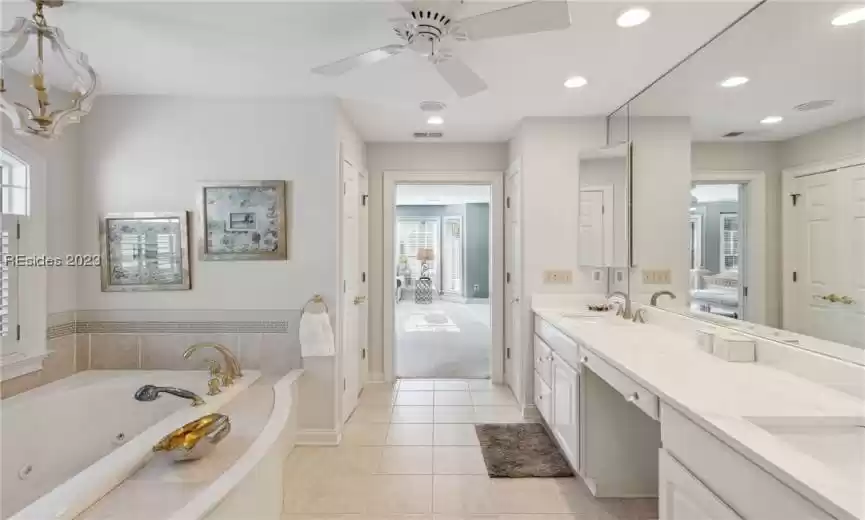 Bathroom featuring tile flooring, ceiling fan with notable chandelier, oversized vanity, and dual sinks