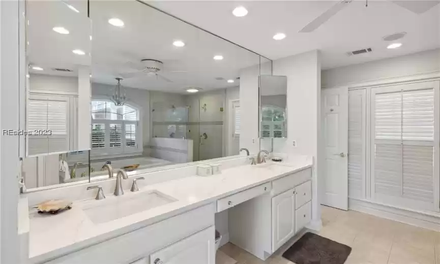 Bathroom with tile flooring, plus walk in shower, ceiling fan with notable chandelier, and double vanity