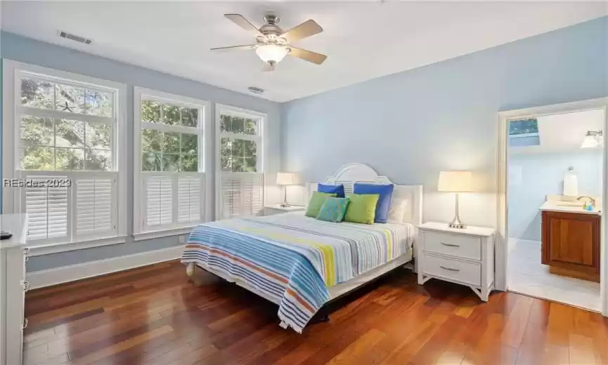 Bedroom featuring ceiling fan, dark hardwood / wood-style flooring, and multiple windows