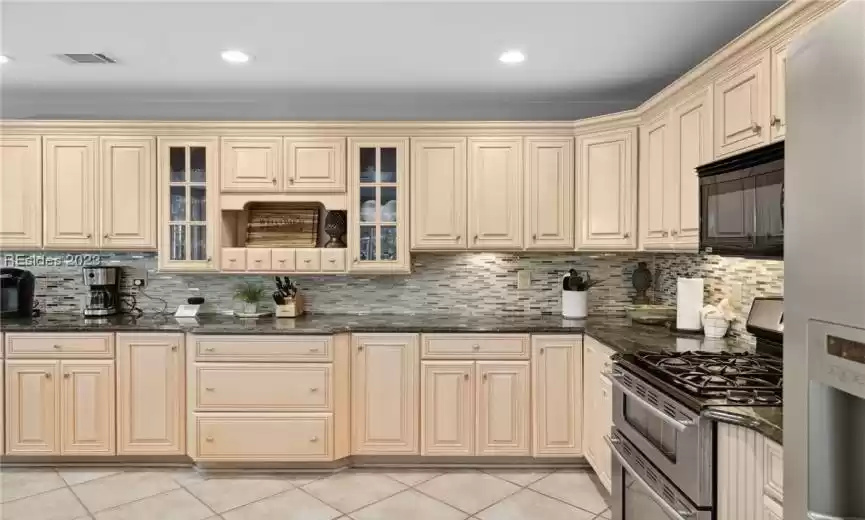 Kitchen featuring range with two ovens, light tile flooring, and backsplash