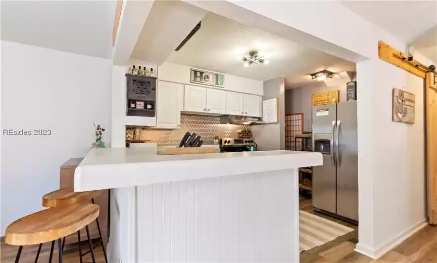 Kitchen featuring stainless steel fridge with ice dispenser, a textured ceiling, light hardwood / wood-style flooring, range, and tasteful backsplash