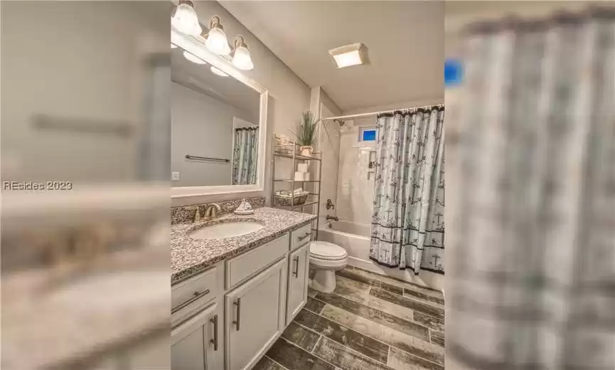 Full bathroom with toilet, vanity with extensive cabinet space, and shower / tub combo with curtain