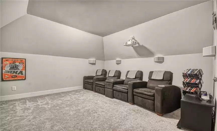 Carpeted home theater featuring lofted ceiling