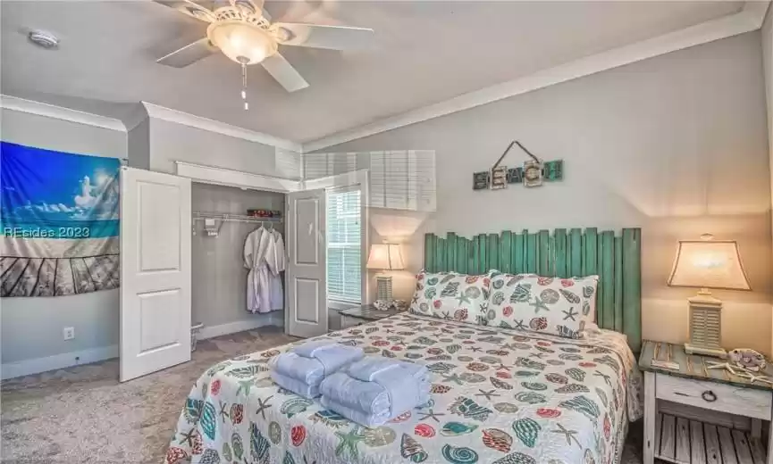 Carpeted bedroom with a closet, ceiling fan, and crown molding