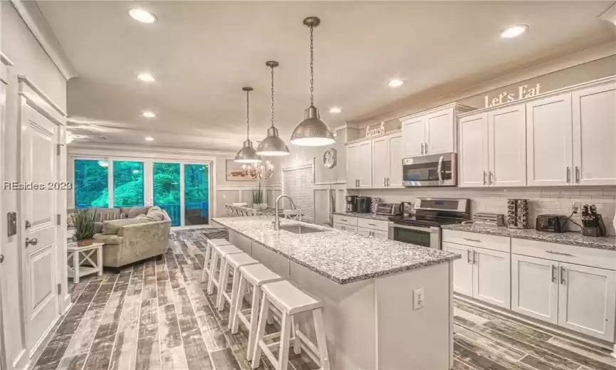 Kitchen featuring an island with sink, white cabinets, and appliances with stainless steel finishes