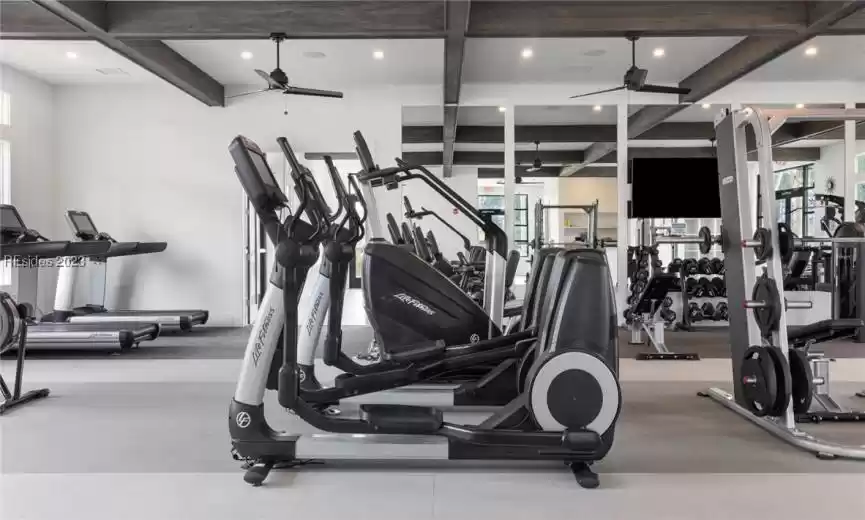 Workout area with a healthy amount of sunlight, coffered ceiling, and ceiling fan