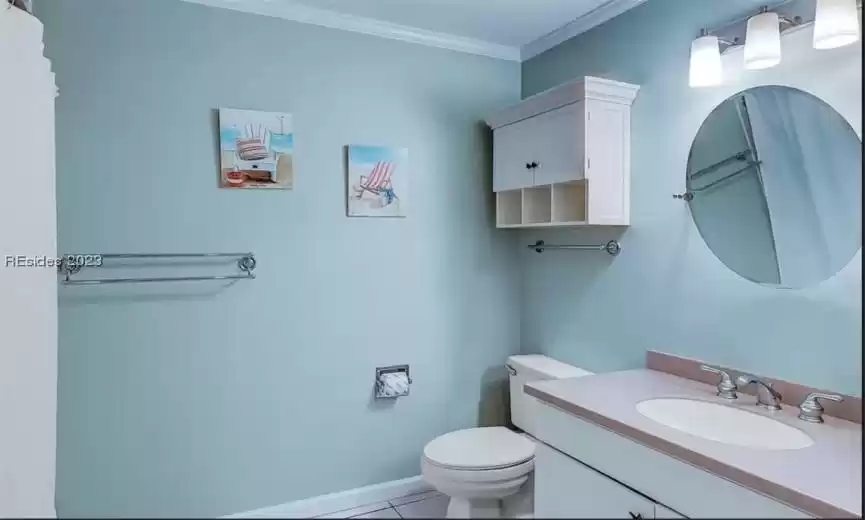 Bathroom with toilet, tile flooring, crown molding, and vanity