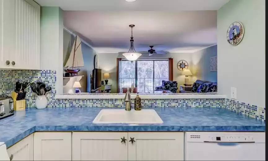 Kitchen with new dishwasher, sink, tasteful  blue pattern backsplash, white cabinetry and ornamental cabinet pulls