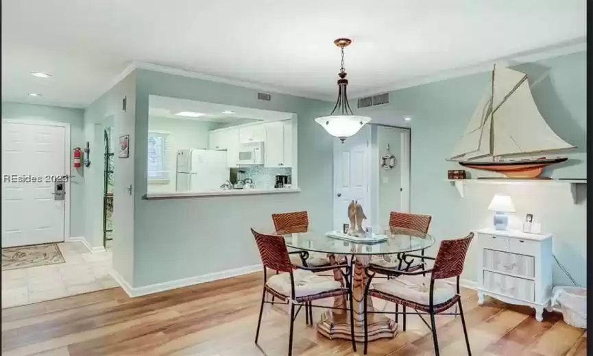 Dining room with light hardwood / wood-style flooring and crown​​‌​​​​‌​​‌‌​‌‌​​​‌‌​‌​‌​‌​​​‌​​ molding