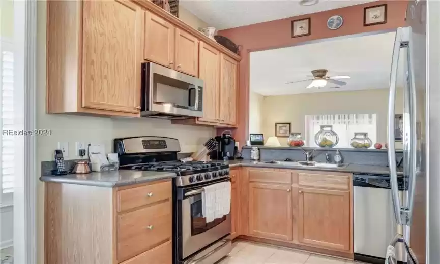 Kitchen with stainless steel appliances, a textured ceiling, sink, light tile floors, and ceiling fan