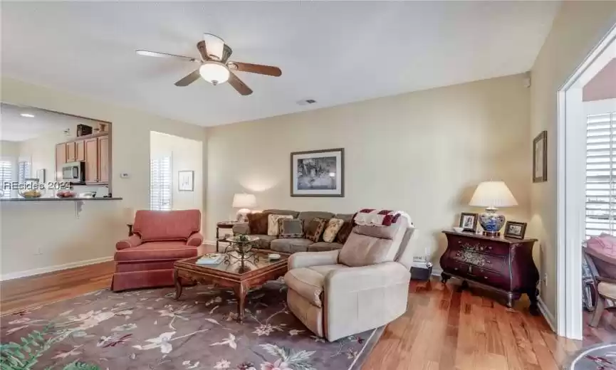 Living room with ceiling fan and hardwood / wood-style flooring