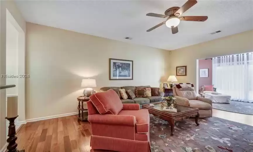 Living room with light wood-type flooring, ceiling fan, and a textured ceiling