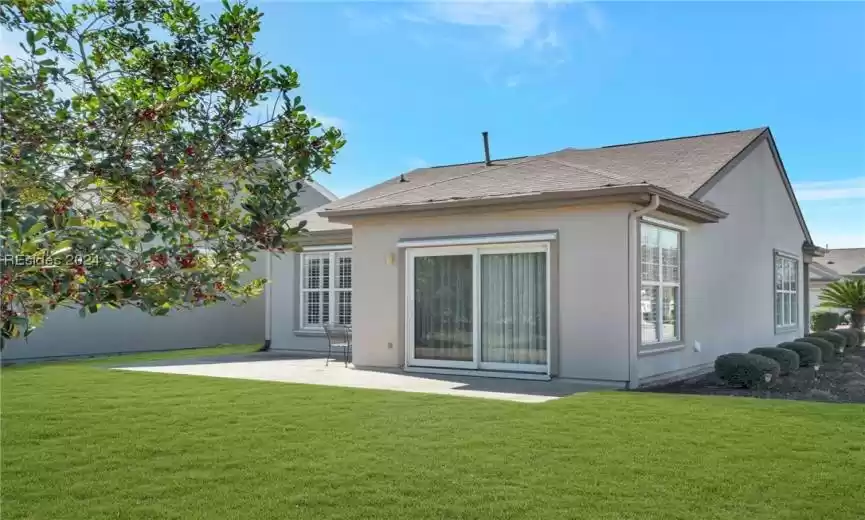Back of property featuring a lawn and a patio