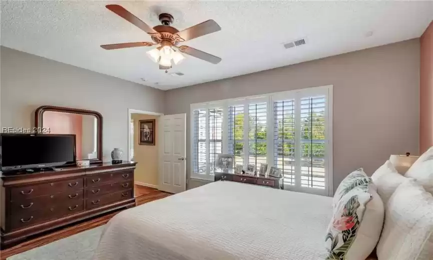 Bedroom featuring ceiling fan, a textured ceiling, and wood-type flooring