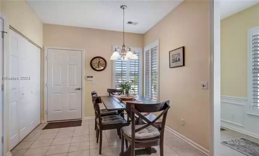 Dining room with light tile flooring, a textured ceiling, and a notable chandelier