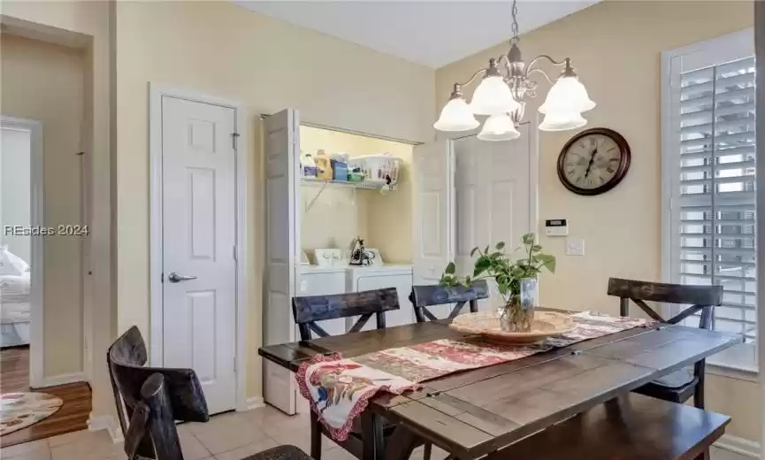Dining room with light hardwood / wood-style flooring, washer and clothes dryer, and a notable chandelier