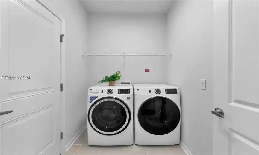 Washroom featuring washer and clothes dryer, light tile floors, and hookup for a washing machine
