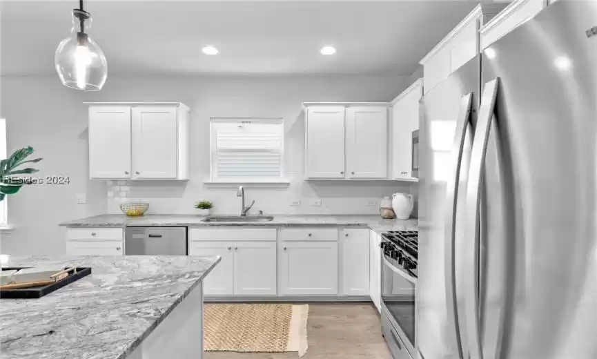 Kitchen featuring white cabinetry, light hardwood / wood-style floors, stainless steel appliances, and sink