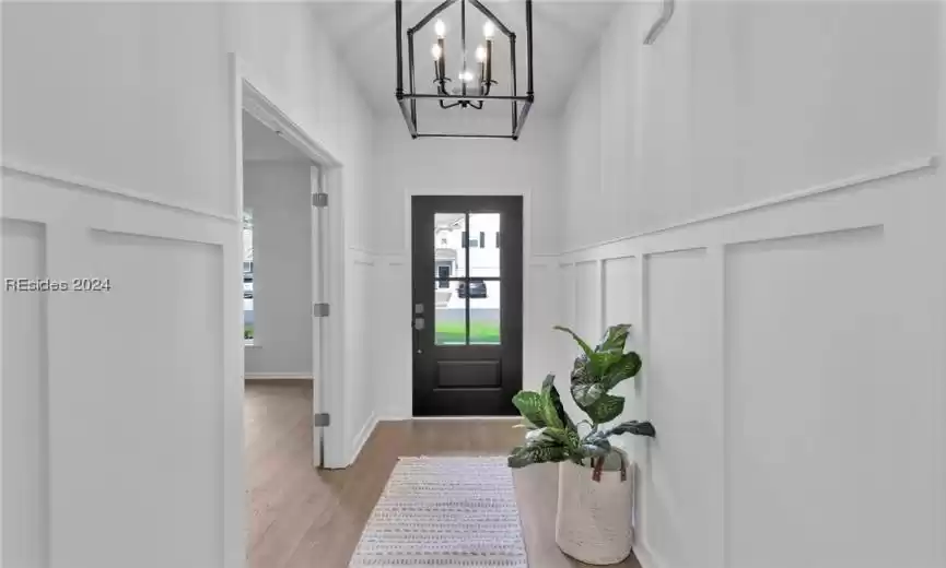 Entryway featuring light hardwood / wood-style flooring, a notable chandelier, and a towering ceiling