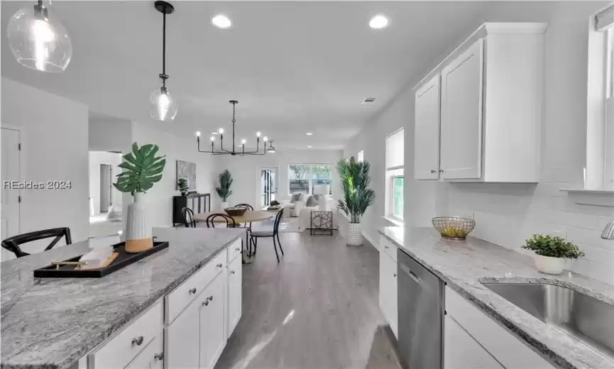 Kitchen featuring SS Appliances, light stone counters, a chandelier, backsplash, and hanging light fixtures