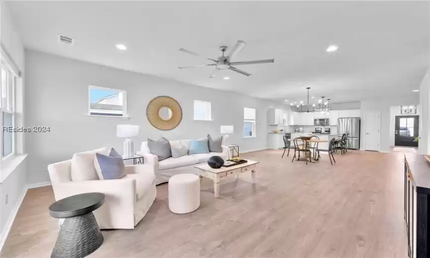 Living area with Luxury LVP wood-style floors and ceiling fan with notable chandelier