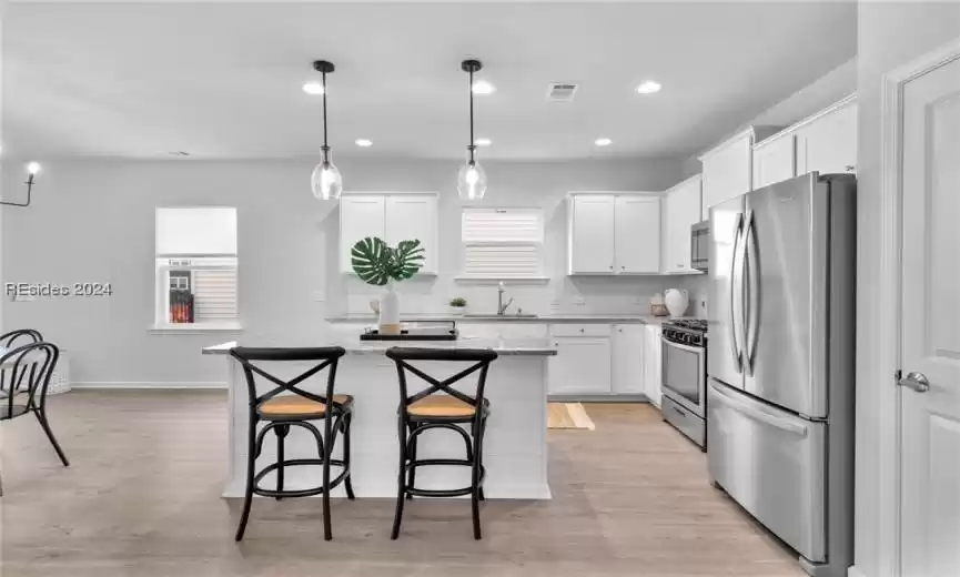 Kitchen featuring light wood-type flooring, plenty of natural light, stainless steel appliances, and white cabinets