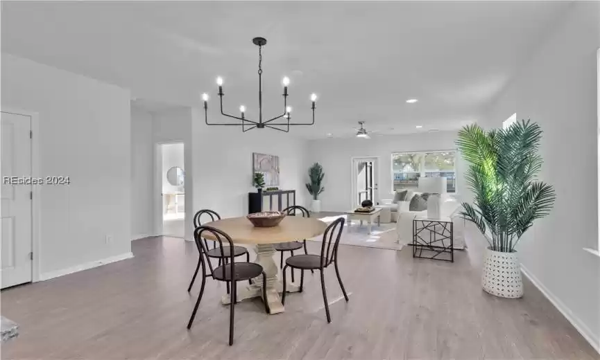 Dining space with light hardwood / wood-style flooring and ceiling fan with notable chandelier