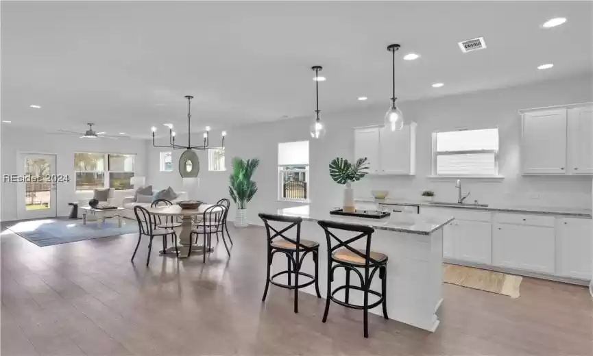 Kitchen featuring white cabinets, sink, pendant lighting, and light wood-type flooring