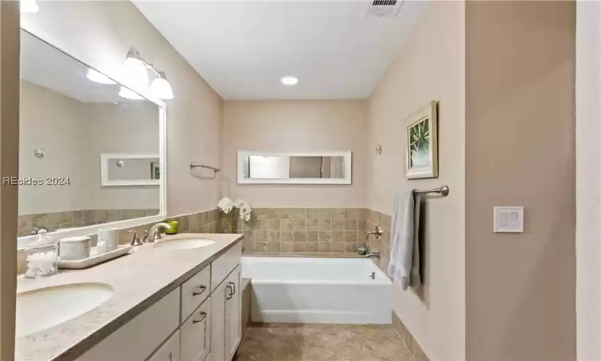 Bathroom with a bathtub, double vanity, and tile flooring
