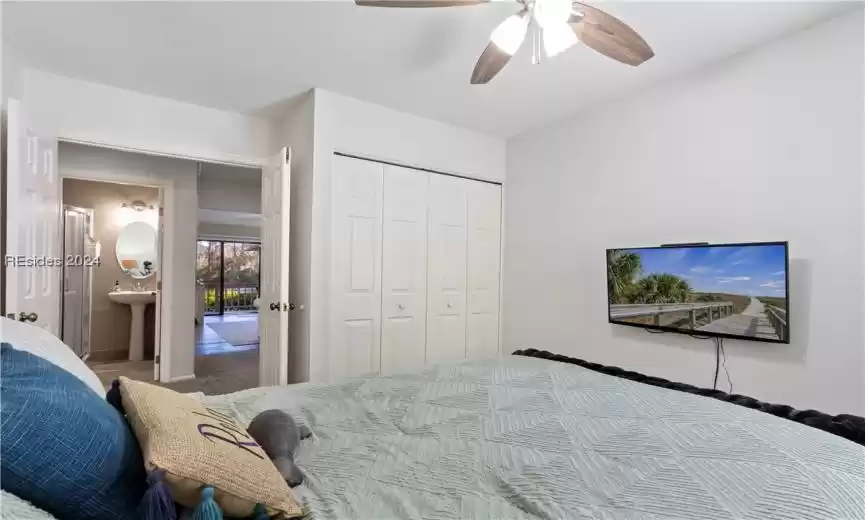 Bedroom featuring carpet flooring, ensuite bath, a closet, sink, and ceiling fan