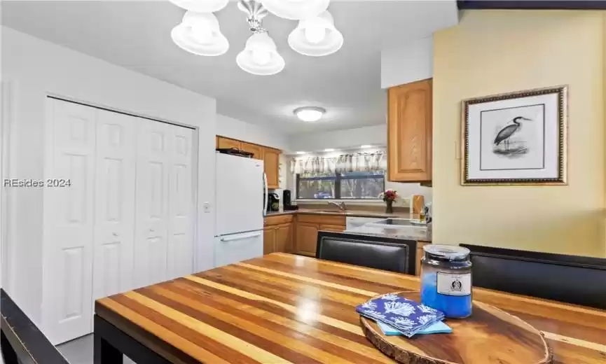 Kitchen featuring light wood-type flooring, a chandelier, dishwashing machine, sink, and white refrigerator