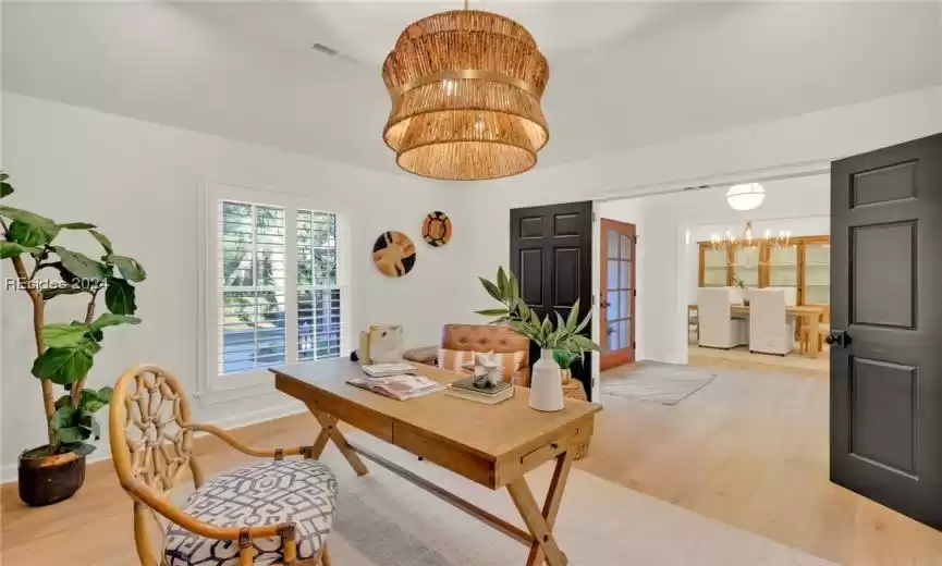 Office with an inviting chandelier and light hardwood / wood-style floors