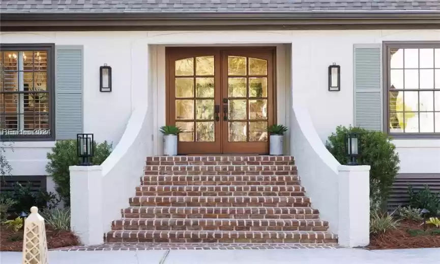 Entrance to property with french doors, beautiful Savannah brick stairs, and on trend lighting fixtures.