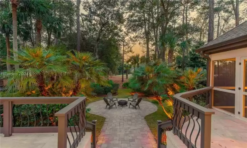 View of patio terrace at dusk, firepit area, and lush landscaping with a view of the golf course.  So many options for outdoor enjoyment at this home.